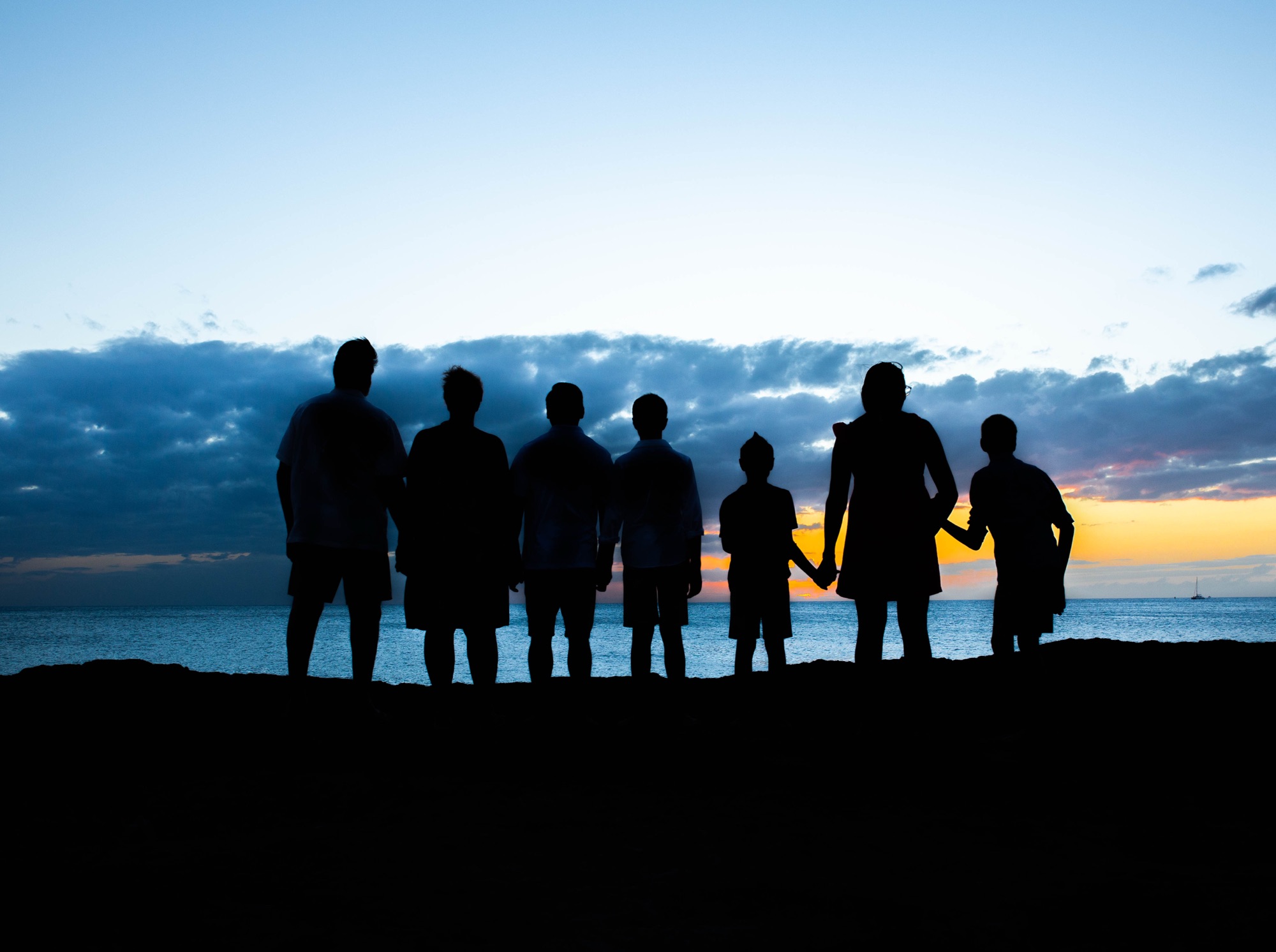 Carter and family members stand together in silhouette beside the ocean at sunset.