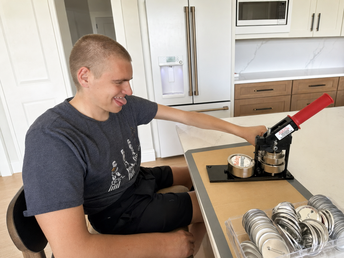 Carter smiles while using a button press to create Carter & Crew products at his worktable.
