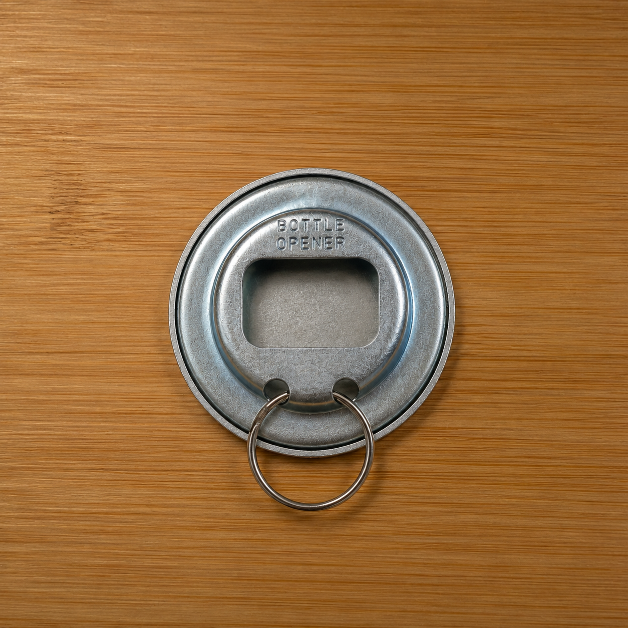 Back of the round metal keychain bottle opener showing the opener mechanism and key ring.